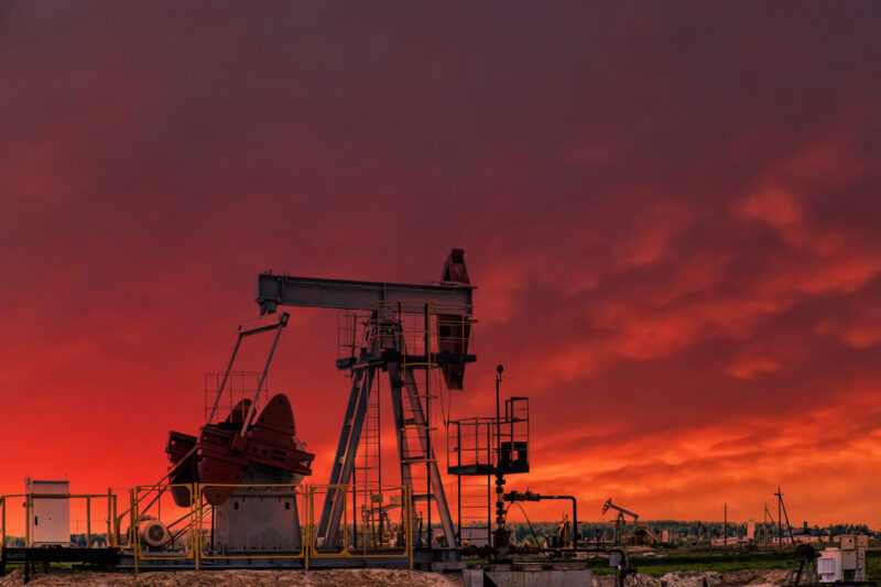 Oil drill rig and pump jack at sunset background. Oil production from ground. Drilling rigs at oilfield in desert. Natural resources, gas. Oil crisis, petroleum industry.