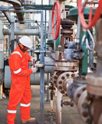 Worker adjusting gauge at oil refinery